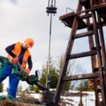 Worker adjusting cementing additives equipment at well site during oil well construction