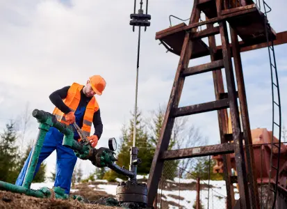 Worker adjusting cementing additives equipment at well site during oil well construction