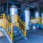 Row of industrial blending tanks with access platforms in oilfield facility