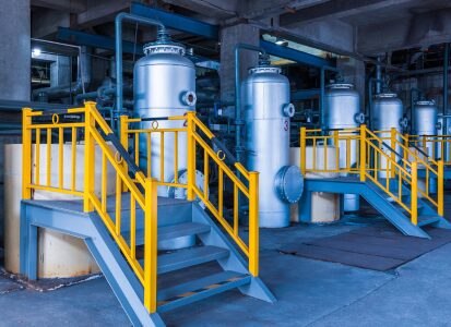 Row of industrial blending tanks with access platforms in oilfield facility