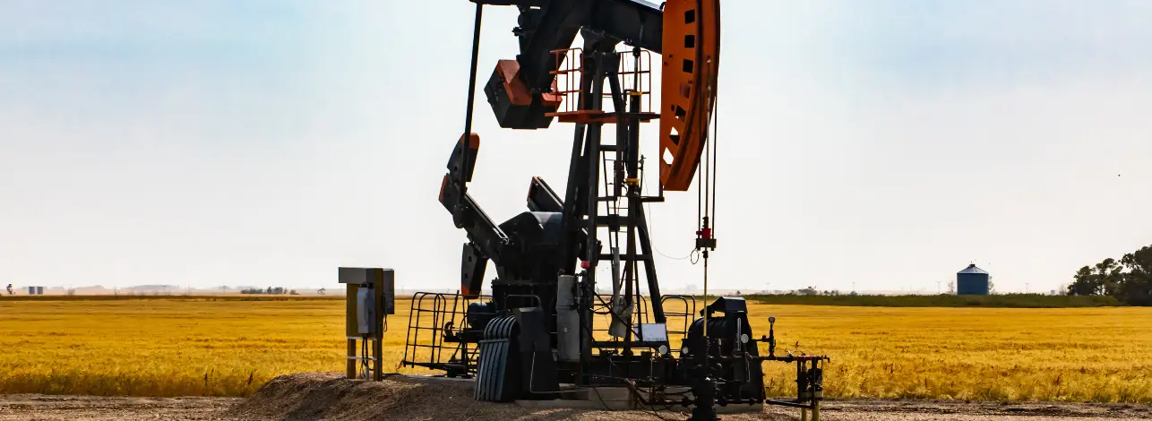 Oil pumpjack in a flat field under clear sky, representing oilfield conditions where cement accelerators improve early strength and operational efficiency.