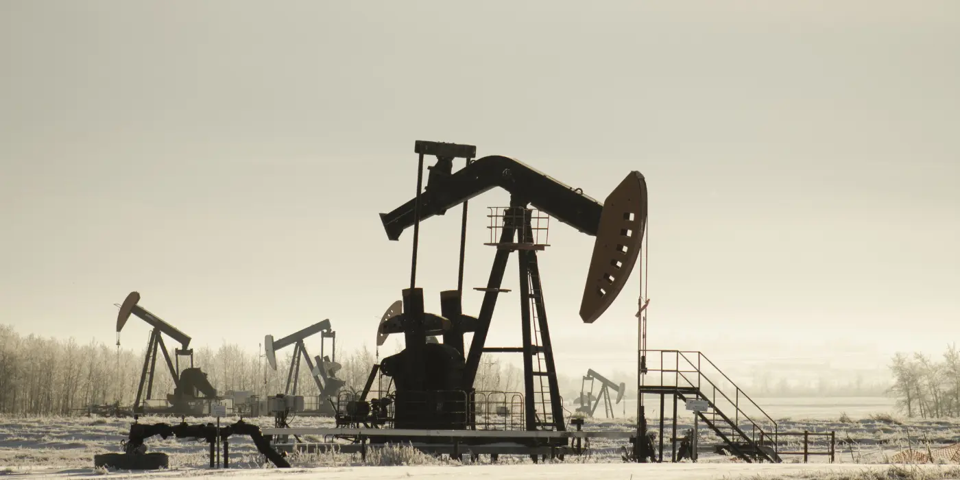 Snow-covered oil field with multiple pumpjacks extracting crude oil, illustrating the environment where surfactants enhance hydraulic fracturing efficiency.