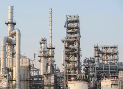 Industrial oil refinery with distillation columns, pipelines, and storage tanks illustrating downstream operations in the oil and gas industry.